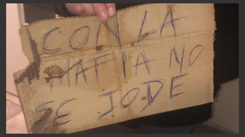 El cartel que dejaron los sospechosos en el acceso del edificio.