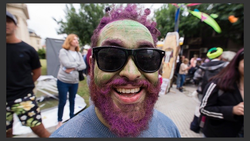 Un hombre con su rostro pintado sonríe para la cámara. 