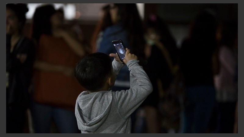Un niño retratando la luna este lunes por la madrugada. 