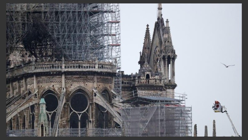 Varios bomberos trabajan en un elevador a la fachada de catedral de Notre Dame.