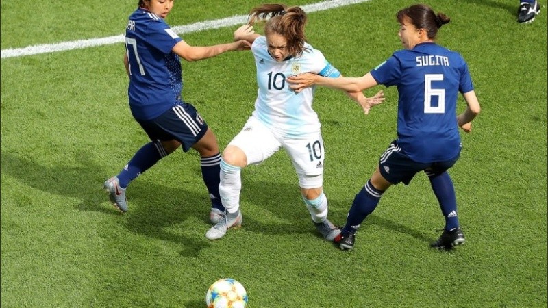 La capitana argentina Banini eludiendo a dos futbolistas japonesas. 