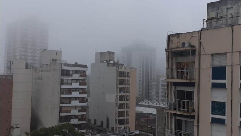 La densa niebla cubriendo los pisos superiores de los edificios en Rosario. 