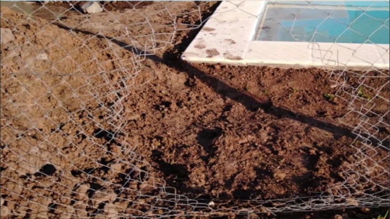 Un agujero en el alambrado para entrar al obrador de una casa. 