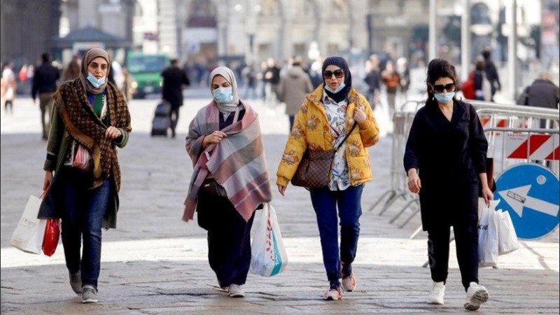 Mujeres caminan por Milán con barbijos. 