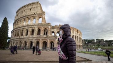 Turistas que usan máscaras faciales caminan cerca del Coliseo en Roma, Italia, país fuertemente golpeado por el coronavirus.