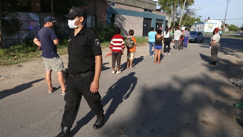 Un policía hace que se respete el distanciamiento en la fila. 