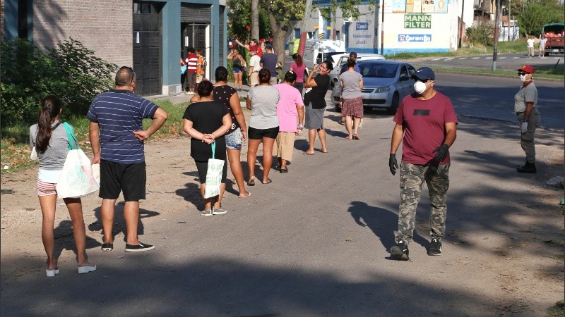 La larga fila de vecinos y vecinas frente a la panadería e intentaban ordenar la cola. 