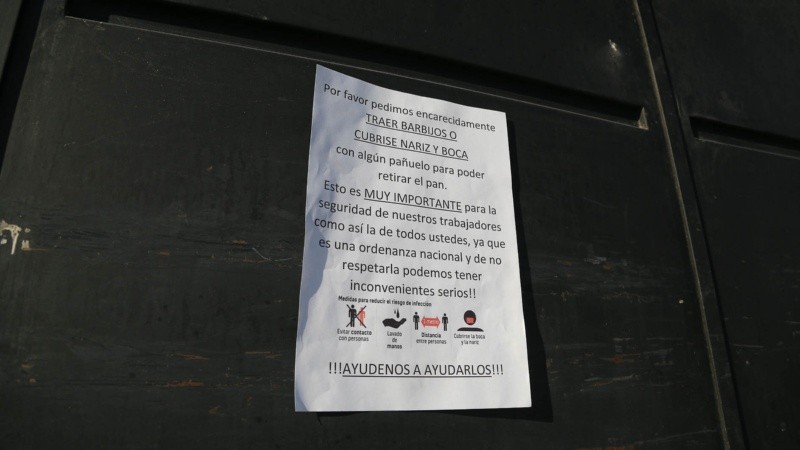 Un cartel en la panadería que recomienda a los que vayan a buscar pan que se cubran la nariz y boca.