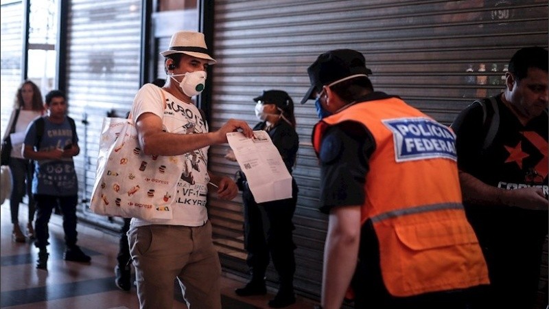 Un hombre muestra un certificado de excepción en Buenos Aires.