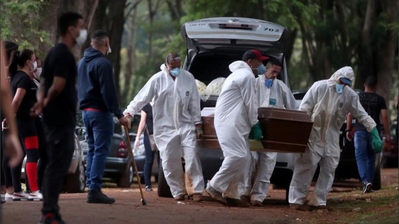 Empleados del servicio funerario entierran a una víctima de covid-19 en el cementerio de Vila Formosa, en Sao Paulo.