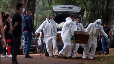 Empleados del servicio funerario entierran a una víctima de covid-19 en el cementerio de Vila Formosa, en Sao Paulo.