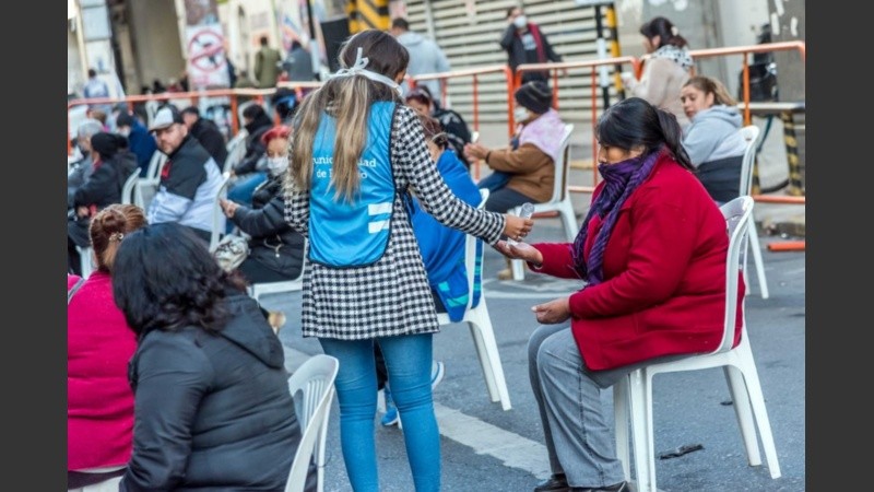 Voluntarios y voluntarias asisten a las personas que deben esperar a cobrar en los bancos. 