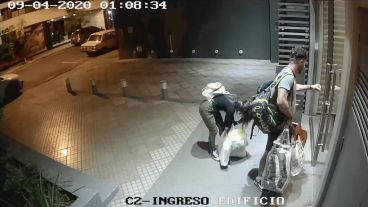 La pareja llegando al edificio, con bolsas de compras y una guitarra, a la 1 de la madrugada.