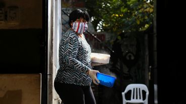 Mirta, una de las que participa activamente en el comedor, sale de la cocina con dos porciones de alimento listos para entregar.