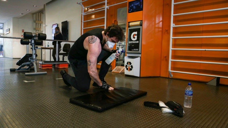 Un hombre limpia su colchoneta tras usarla. Es parte del nuevo protocolo de salud.