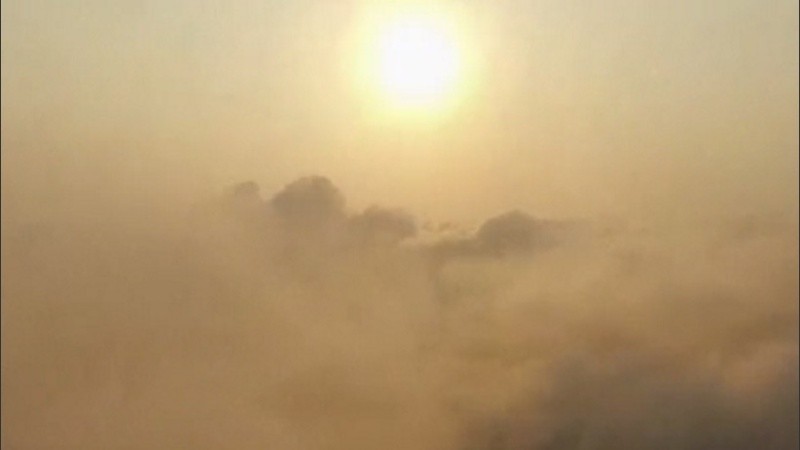 Un sol entre nubes, niebla y humo. 