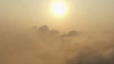 Un sol entre nubes, niebla y humo.