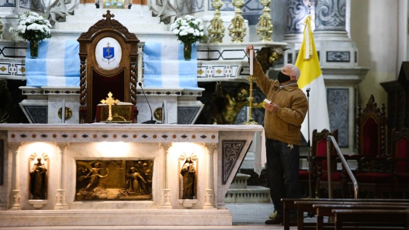 Uno de los asistentes de la Catedral enciende las velas del altar para iniciar la misa. 