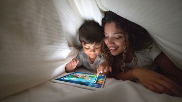 Mother and son playing on a digital tablet in bed