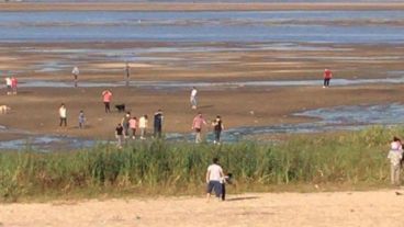 Mucbas personas intentan cruzar la laguna caminando ante la bajante de las aguas.
