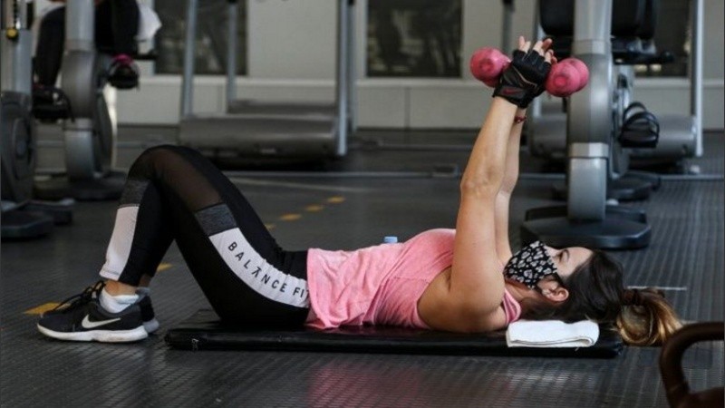 Una joven levanta pesas en un gimnasio céntrico.
