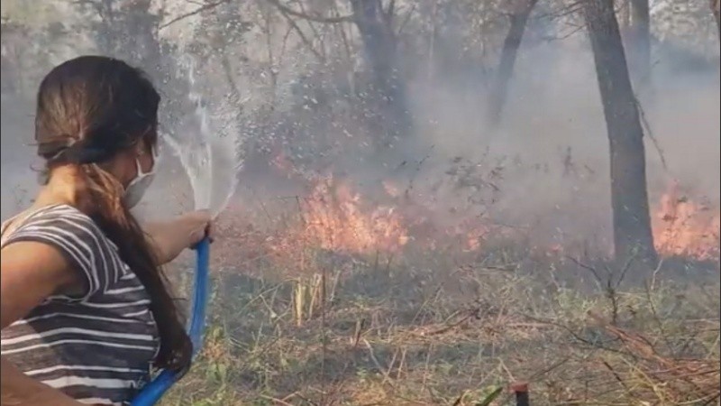 Una voluntaria le da pelea al fuego con una manguera. 