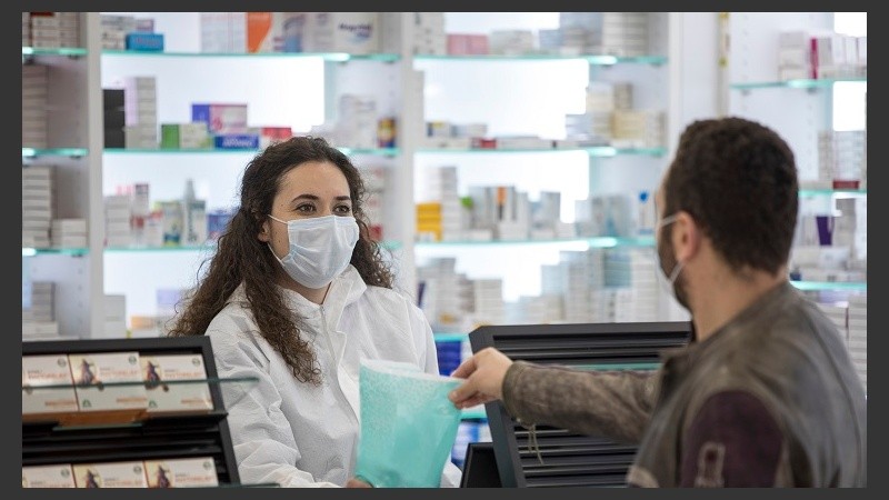 Female pharmacist wearing a surgical mask gives medication to the patient