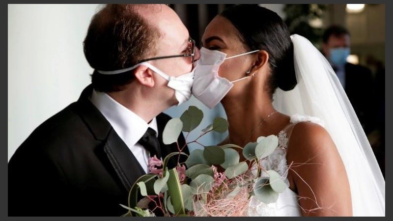 Los recién casados Diego Fernandes y Deni Salgado se besan con máscaras.