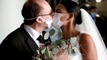 Los recién casados Diego Fernandes y Deni Salgado se besan con máscaras.