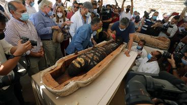 La apertura de un sarcófago con mucha gente alrededor.