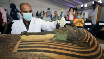 La apertura de un sarcófago con mucha gente alrededor.