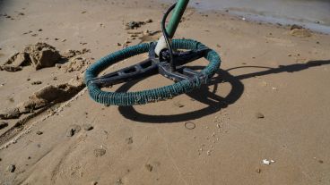 El plato del detector de metales "barriendo" un sector de la playa.