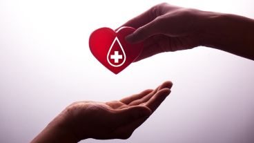 A hand gives a red heart to a hand - blood donation,world blood donor day