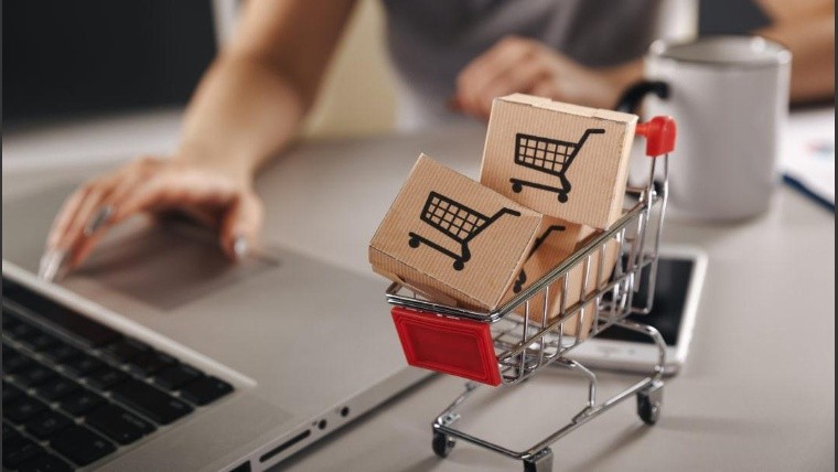 Online shopping . ecommerce and delivery service concept : Paper cartons with a cart or trolley logo on a laptop keyboard, depicts customers order things from retailer sites via the internet.