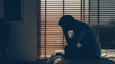 Sad businessman sitting head in hands on the bed in the dark bedroom with low light environment, dramatic concept, vintage tone color