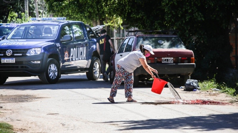 Una mujer limpia la sangre que dejó un homicidio. Hechos de violencia se multiplican en Rosario. 