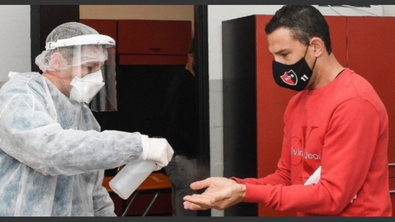 Maxi Rodríguez recibe alcohol al ingresar al entrenamiento. Imágenes del inicio de la pandemia que, según el médico de la LiIga, dejaron de verse.
