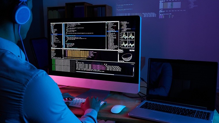Programmer in headphones checking his code on computer screen