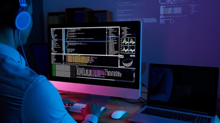 Programmer in headphones checking his code on computer screen