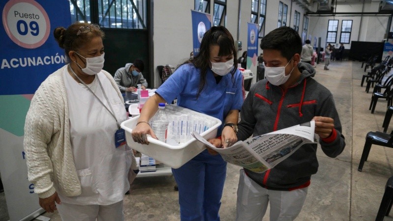 Un voluntario le muestra el diario a sus colegas: salió una foto suya en la segunda página.