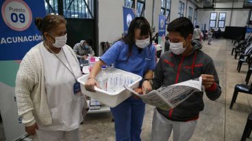 Un voluntario le muestra el diario a sus colegas: salió una foto suya en la segunda página.