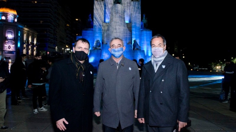 El intendente Pablo Javkin acompañado por Diego Zehnder y Gustavo Badosa, con el hermoso Monumento iluminado detrás.