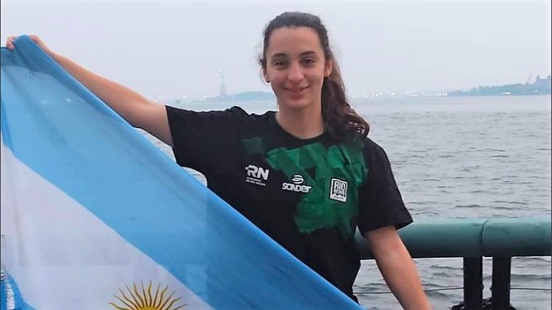 Ailén posa con la bandera argentina, con la Estatua de la Libertad de fondo.