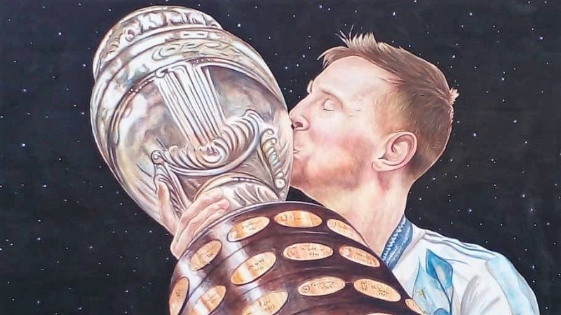 Leo y su anhelado trofeo con la celeste y blanca, en una pared de barrio Alvear.