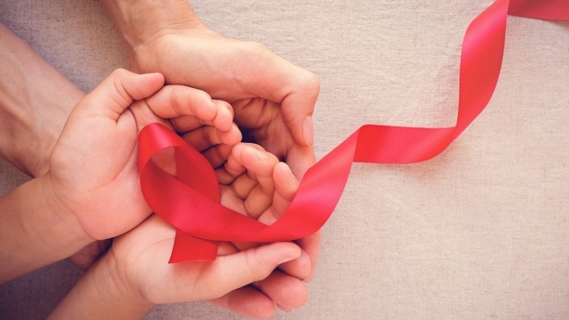 adult and child hands holding red ribbon, hiv awareness concept, world AIDS day
