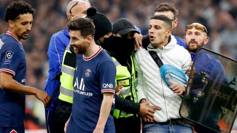 Messi se retira de la escena mientras el intruso, ya capturado por los agentes de seguridad, parece decirle algo.
