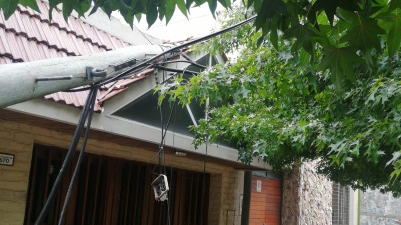 Poste caído sobre una casa. 