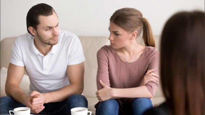 Young couple at psychologist, looking at each other with hate