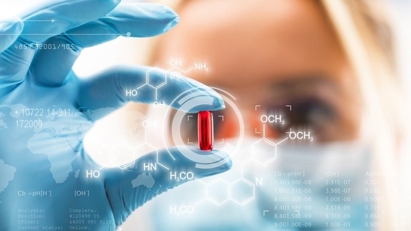 Young attractive female scientist holding a red transparent pill