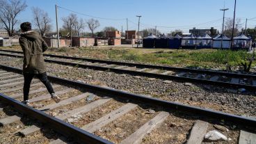 Un joven camina por las vías. Detrás el operativo multiagencial.